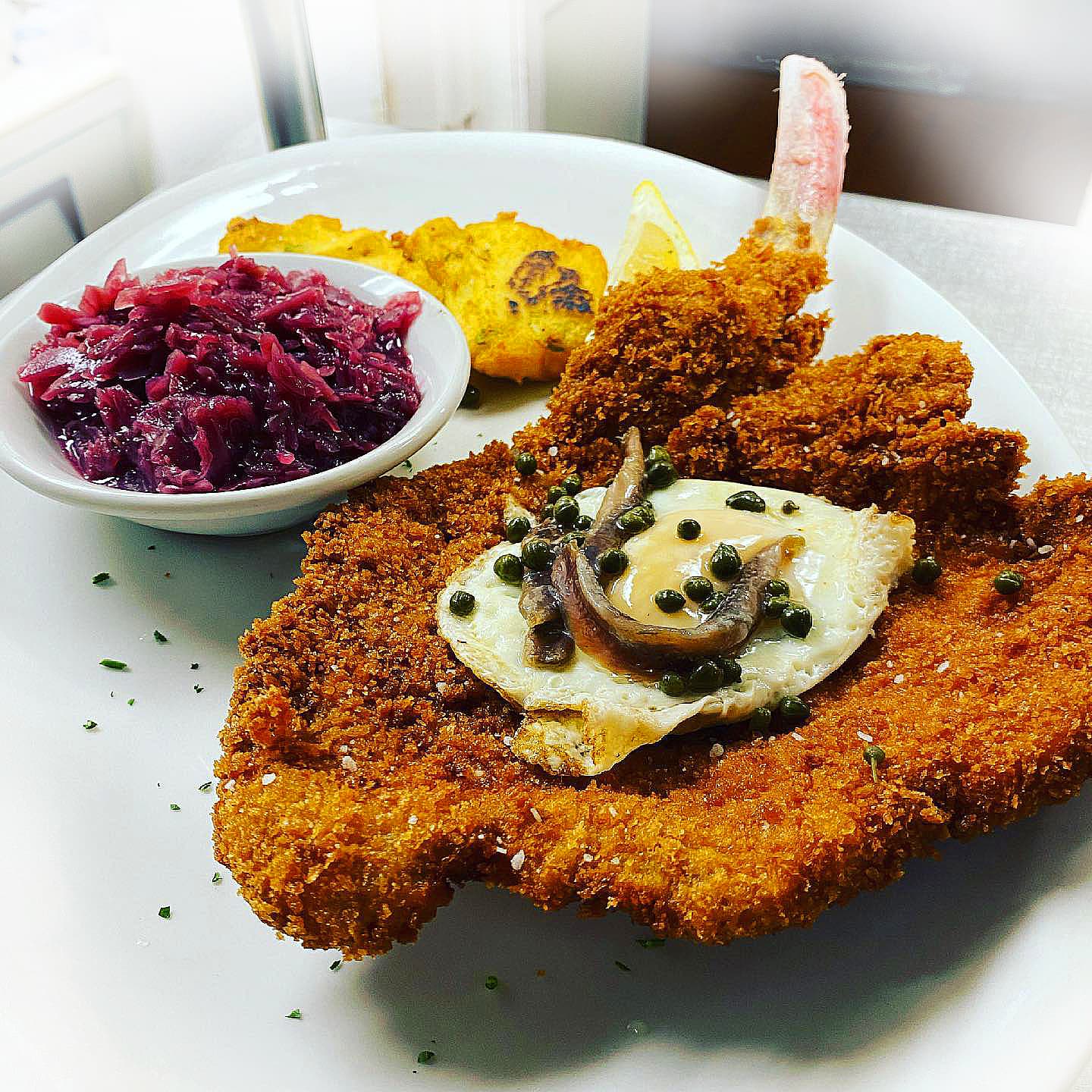 Breaded schnitzel topped with a fried egg and capers, served with red cabbage